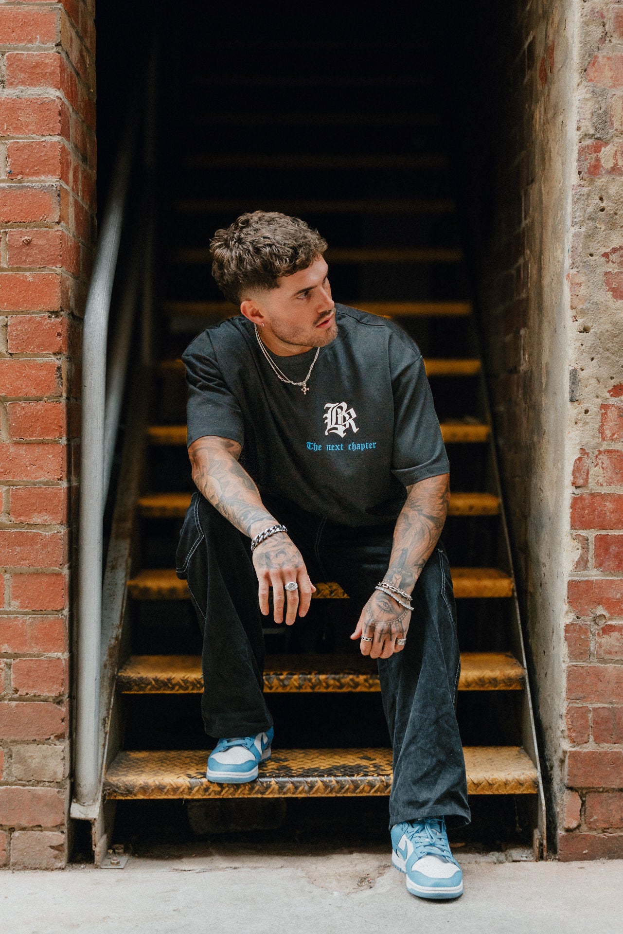 Male model wearing black, white and blue streetwear tee. Urban setting