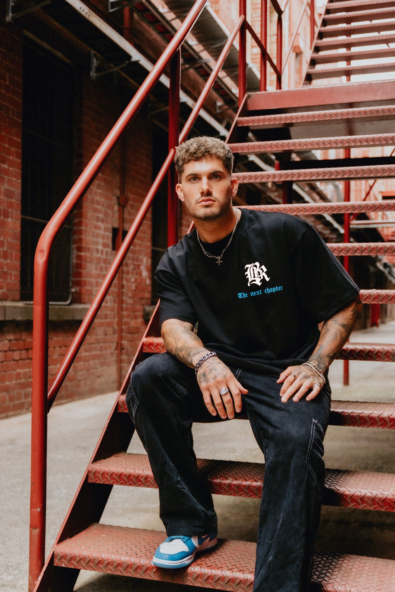 Male model wearing black, white and blue streetwear tee. Urban setting