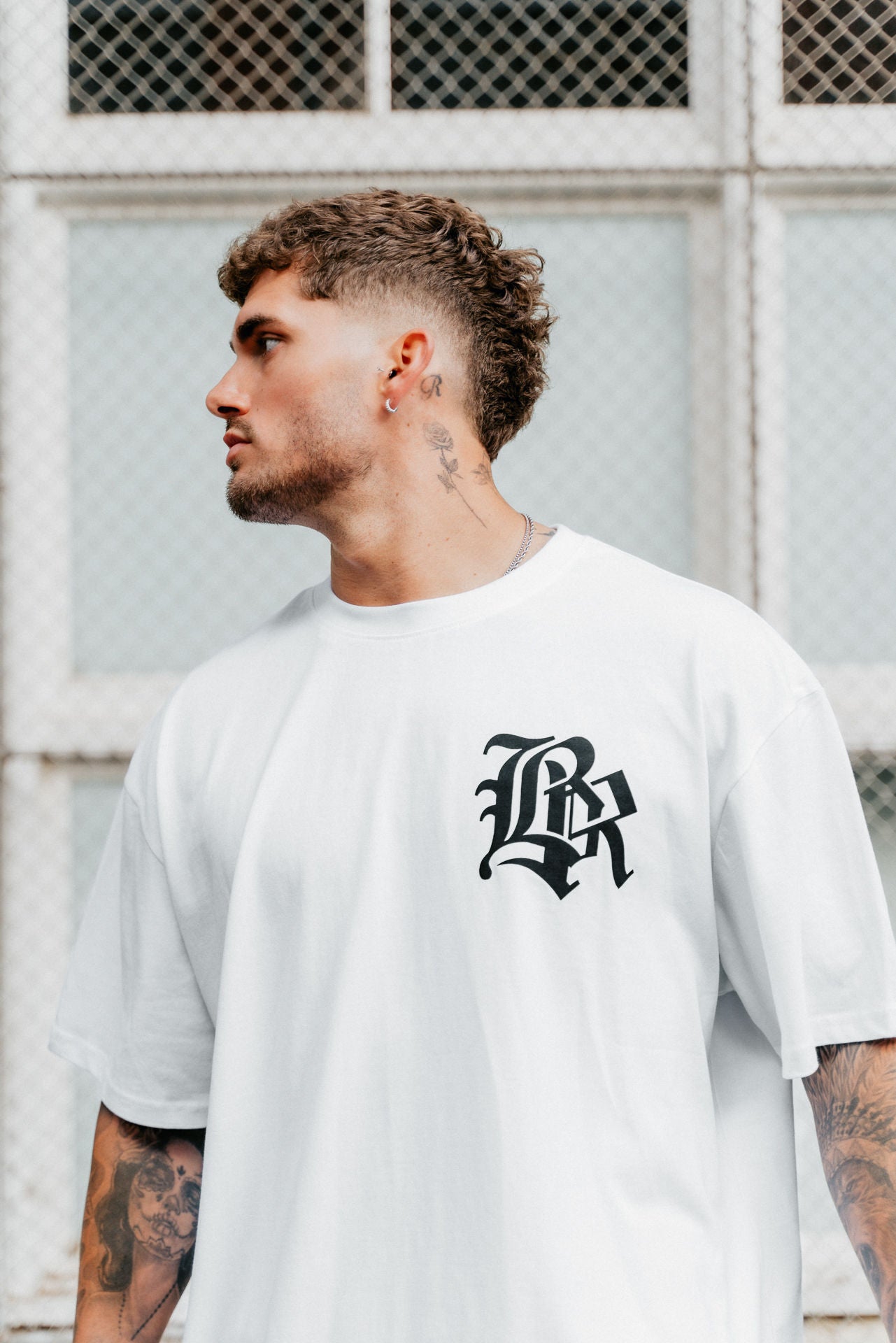 male model looking away wearing white t-shirt in an urban setting