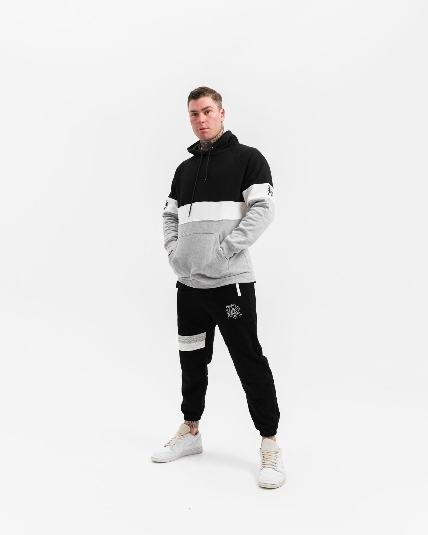 male model wearing black, grey and white panel jumper, white background