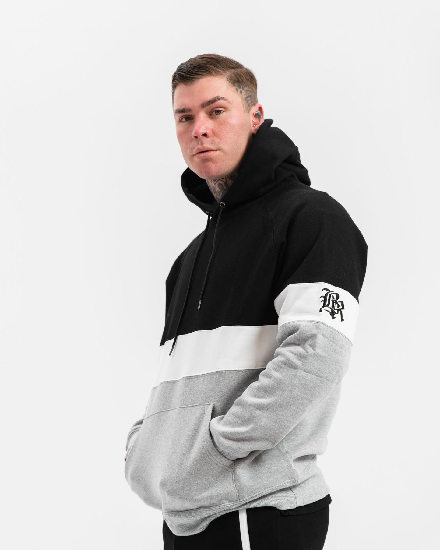 male model wearing black, grey and white panel jumper, white background