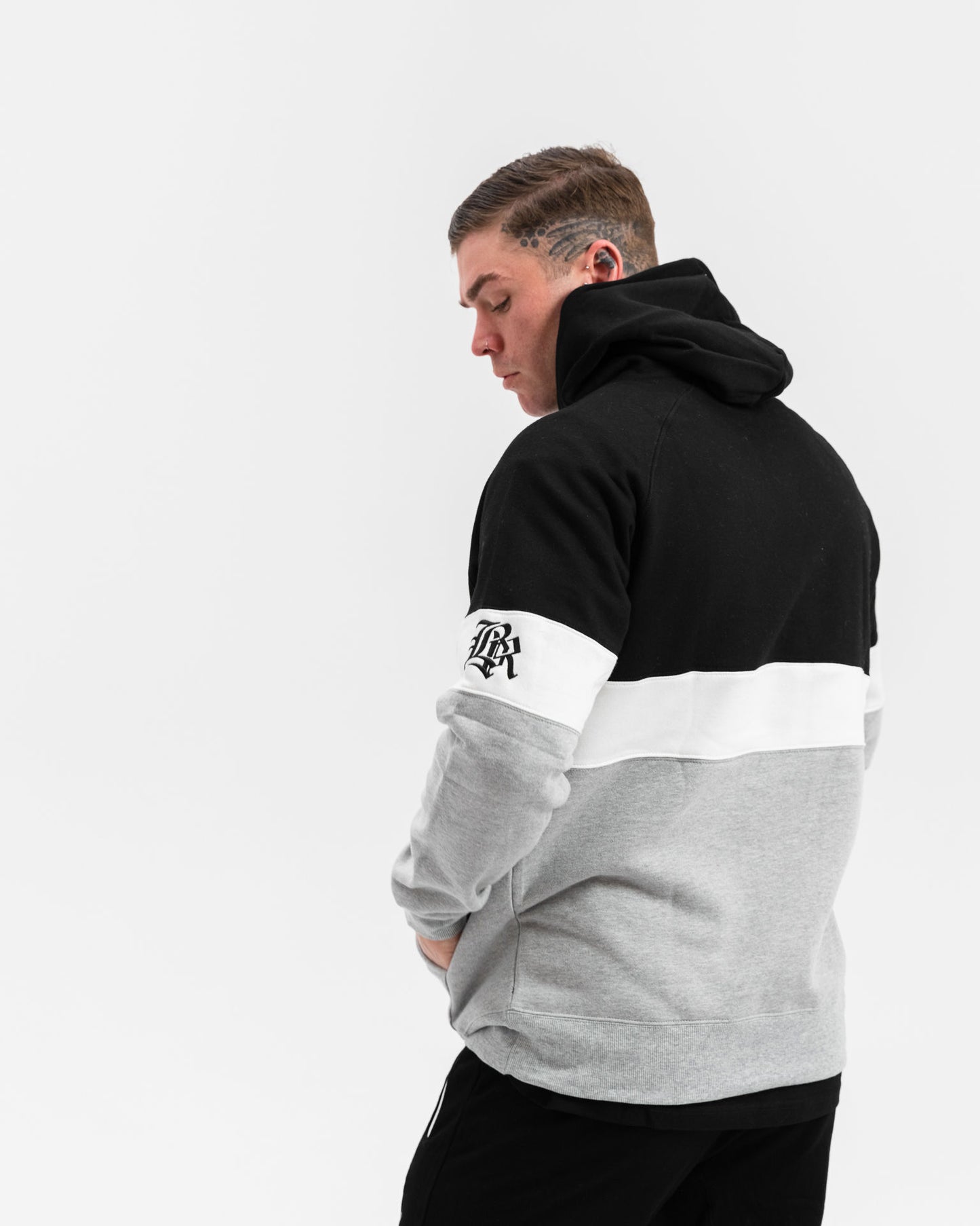 male model wearing black, grey and white panel jumper, white background