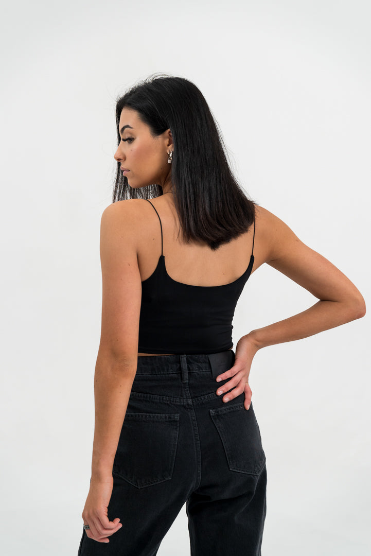 female model, facing away, with black singlet and jeans, white background