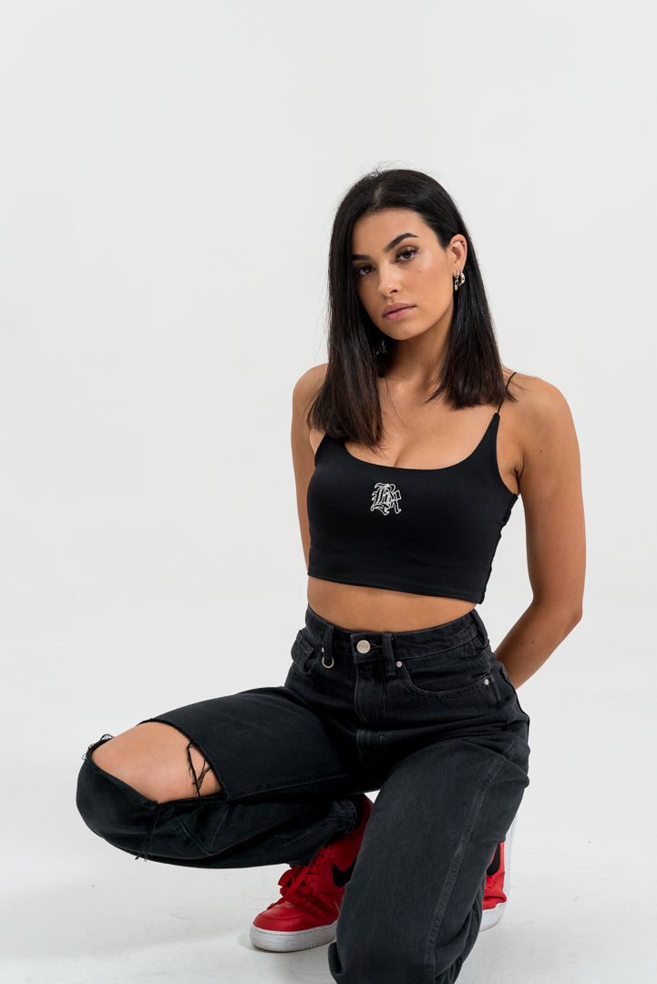 female model kneeling with black singlet and jeans, red shoes, white background