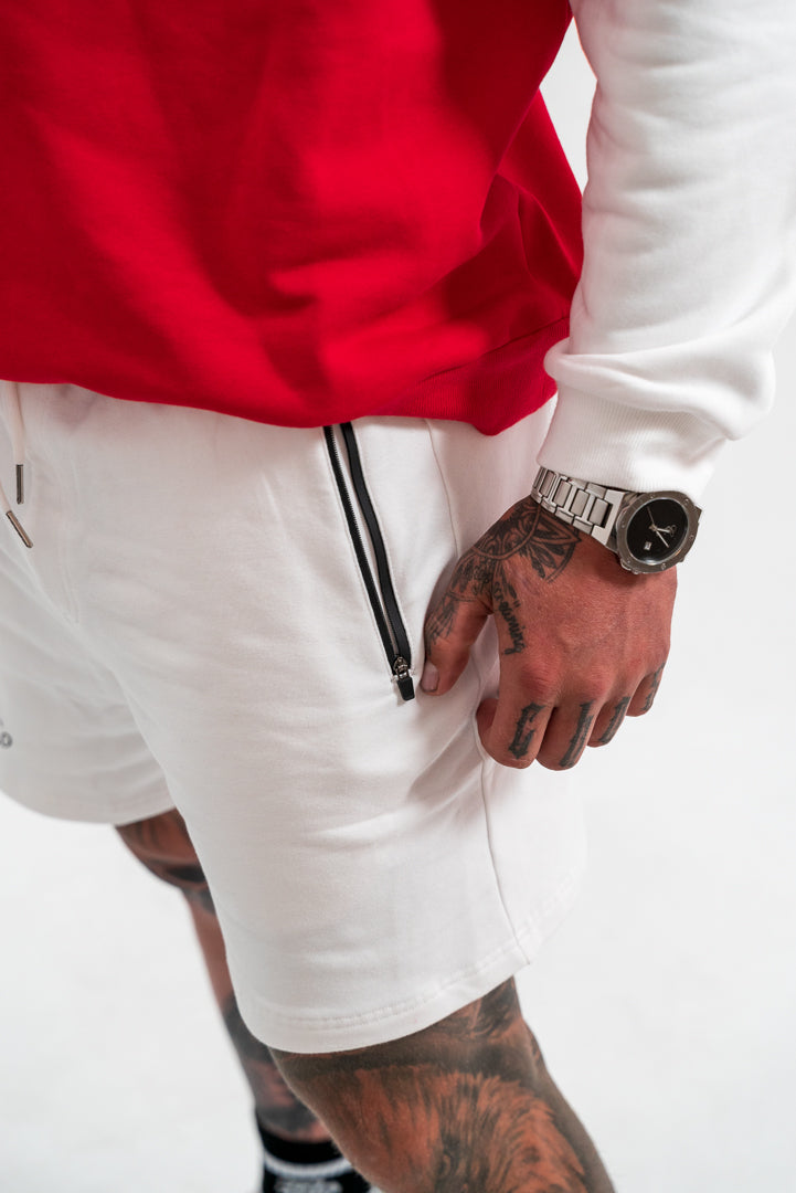 white shorts and red and white top, tattoos, watch