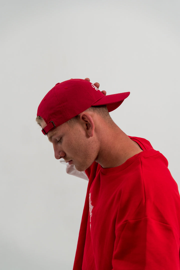 male model wearing red hat and red and white crewneck jumper, white background