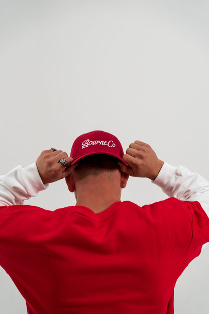 male model wearing red hat and red and white crewneck jumper, white background