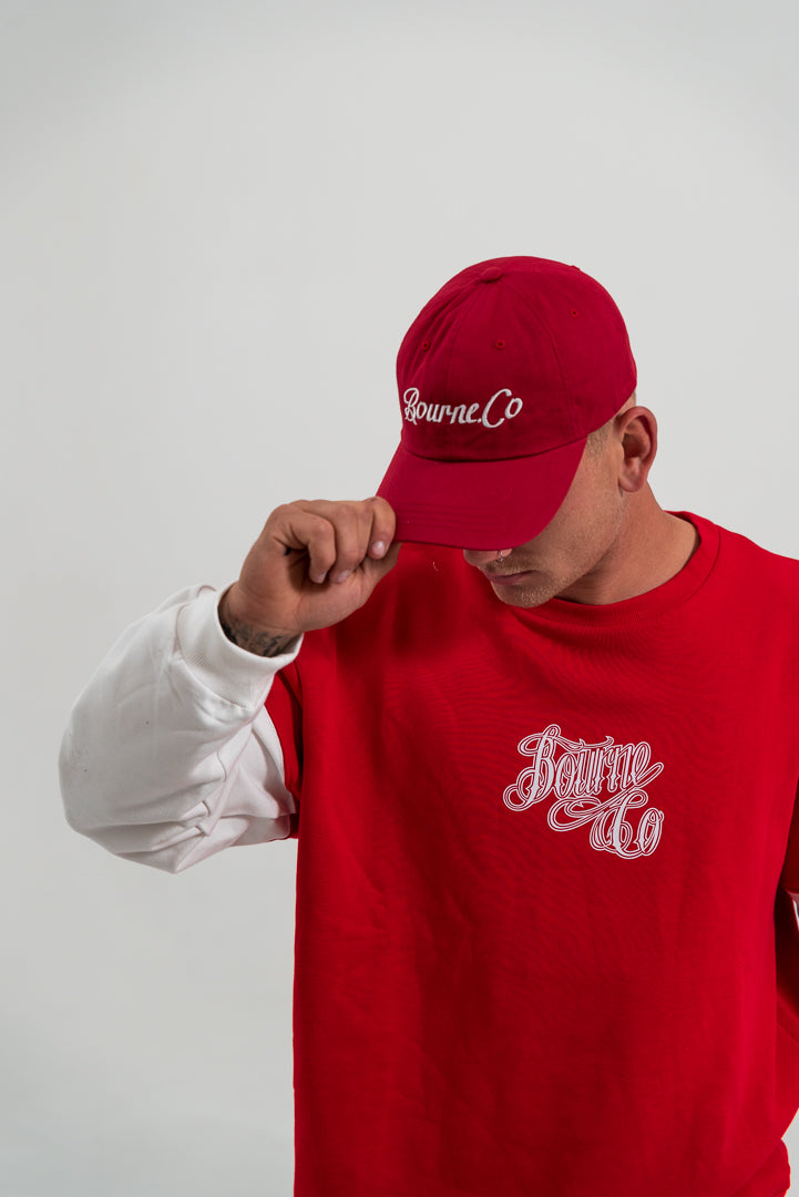 male model wearing red hat and red and white crewneck jumper, white background