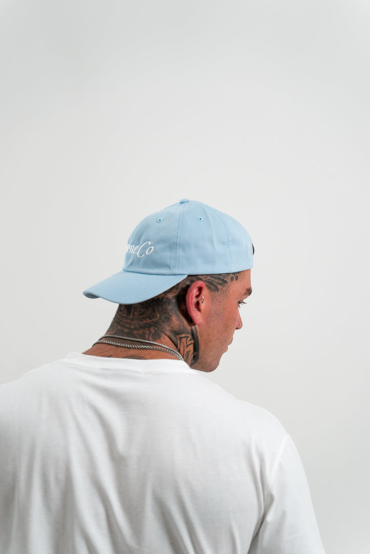 male model wearing a blue hat, tattoos, chains, white background