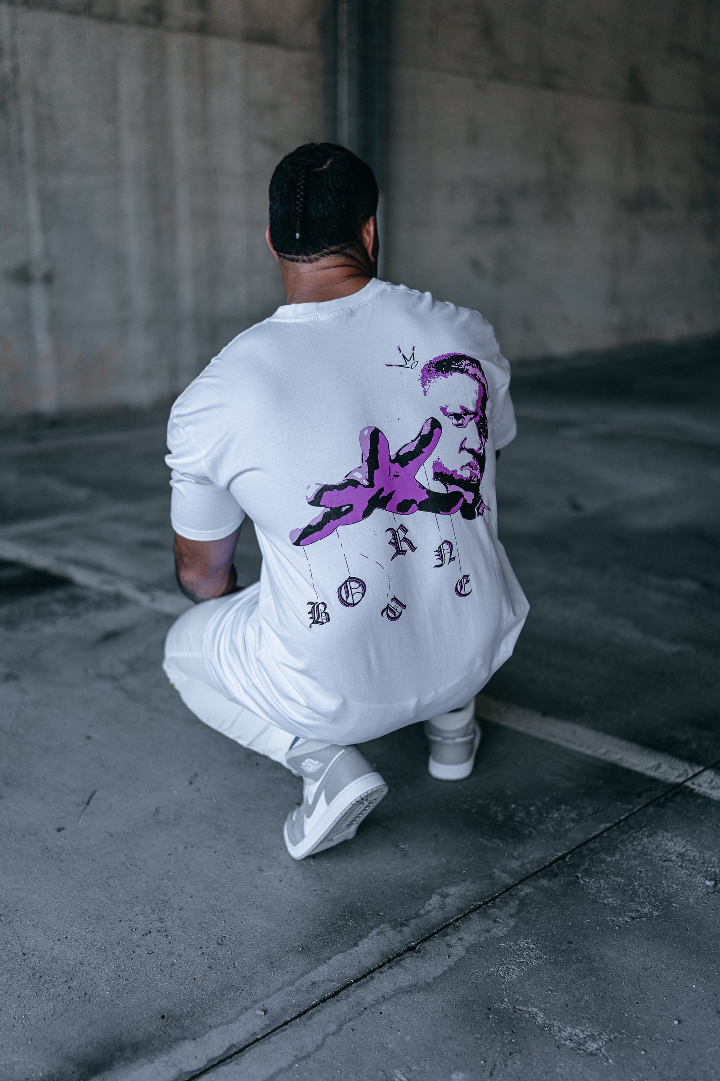 male model facing away, with a white biggie smalls t-shirt on and black shorts, urban setting, 