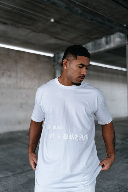 male model looking down, with a white t-shirt on, urban setting