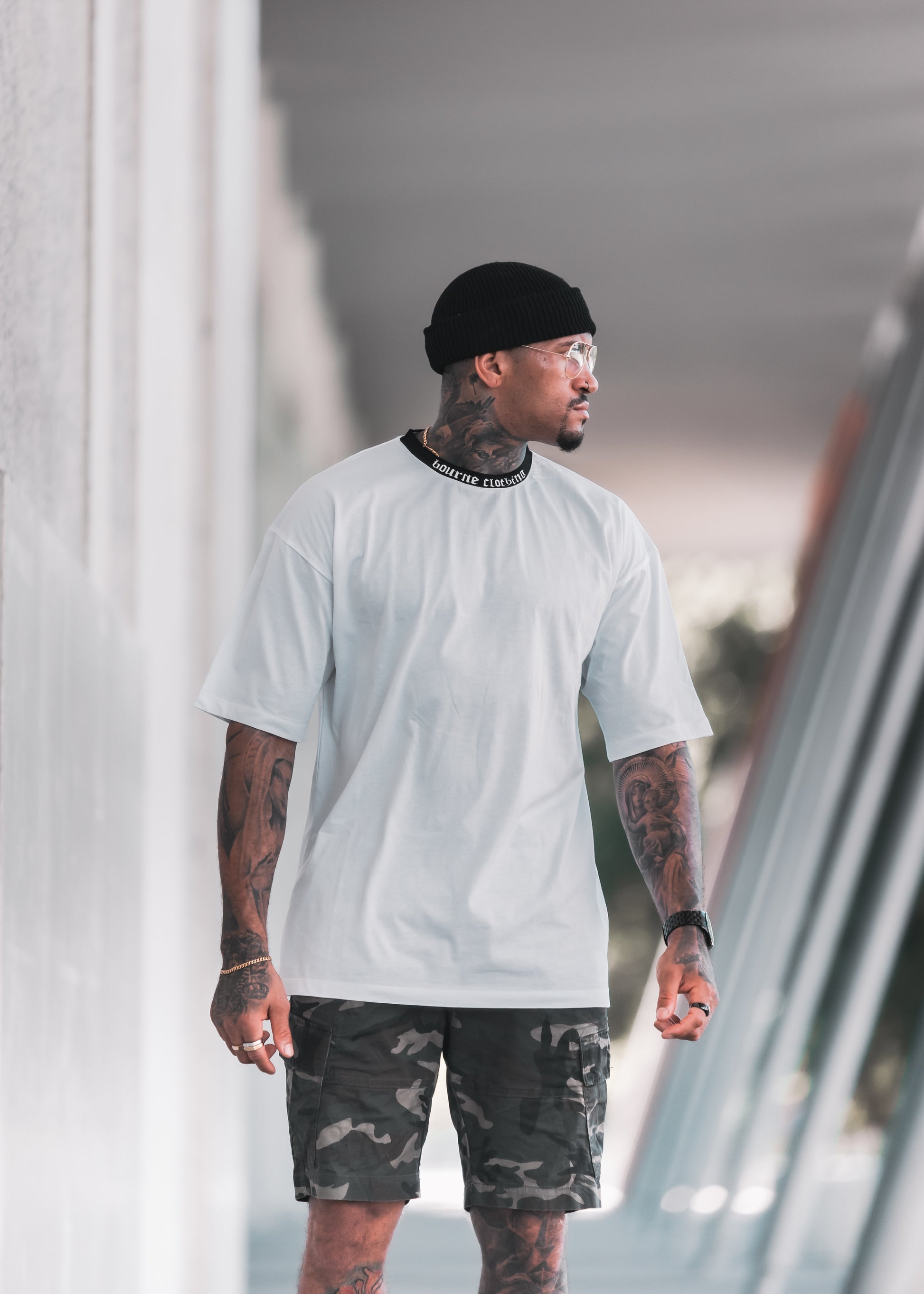 male model with white t-shirt and camouflage shorts in an urban setting