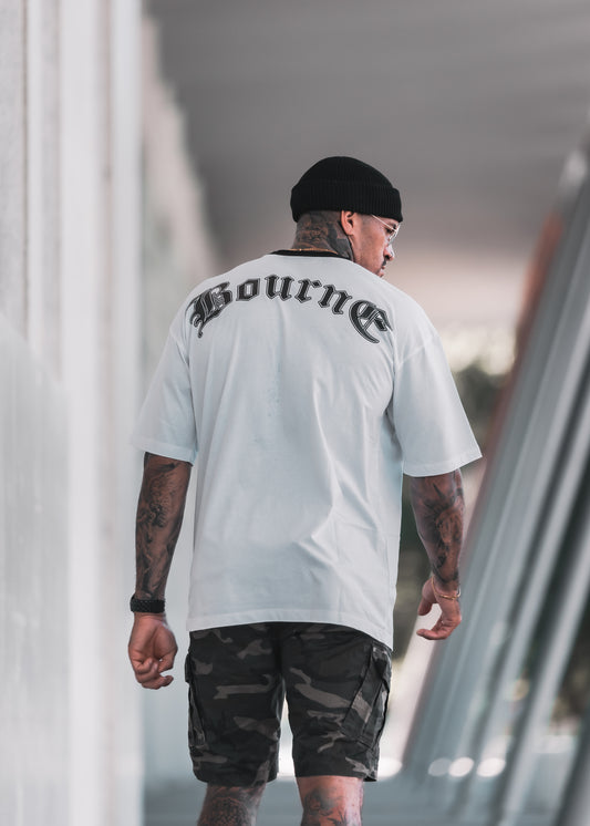 male model with white t-shirt and camouflage shorts, facing away in an urban setting 